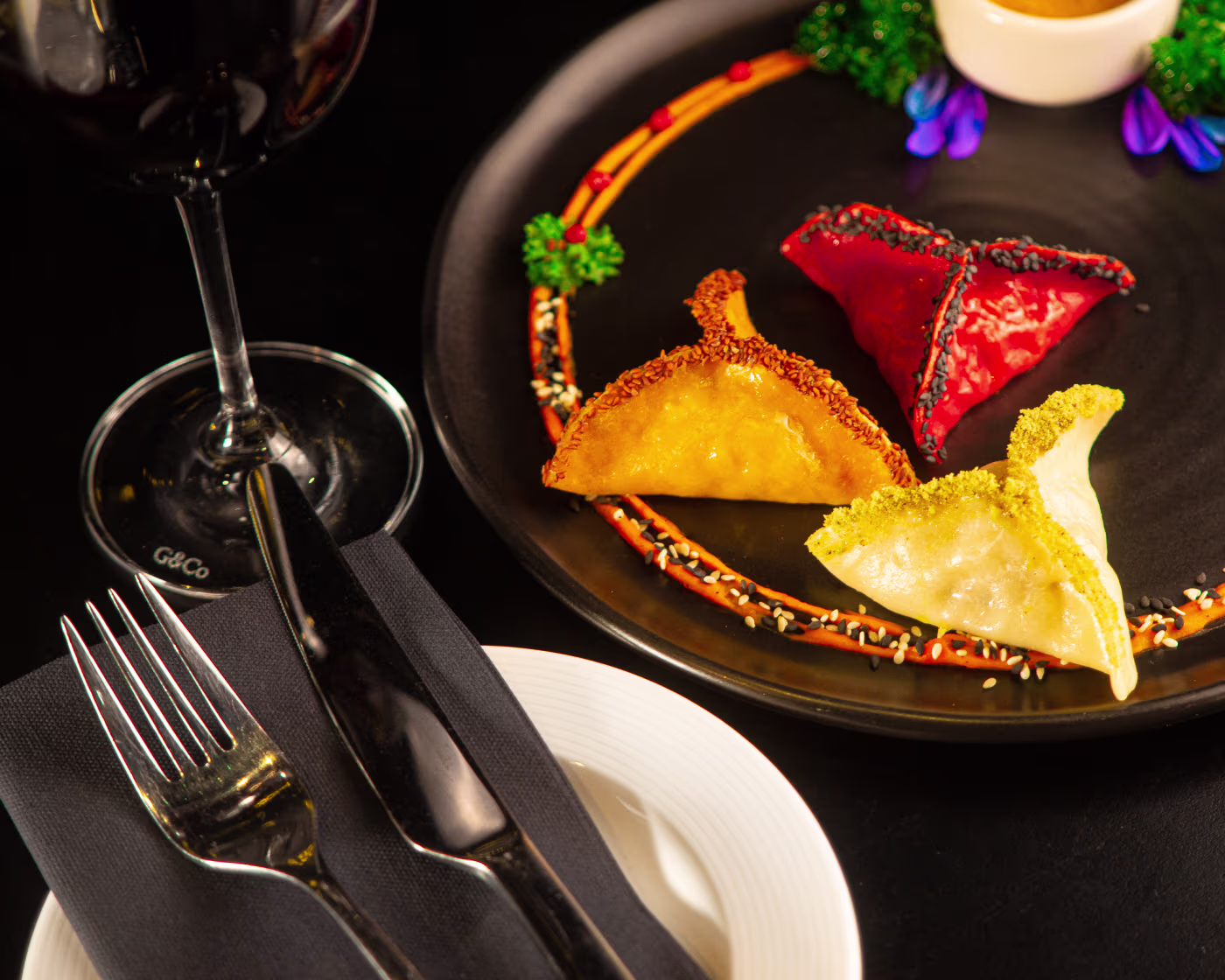 Samosas con chutneys de colores en un plato oscuro en Tantra, Edimburgo